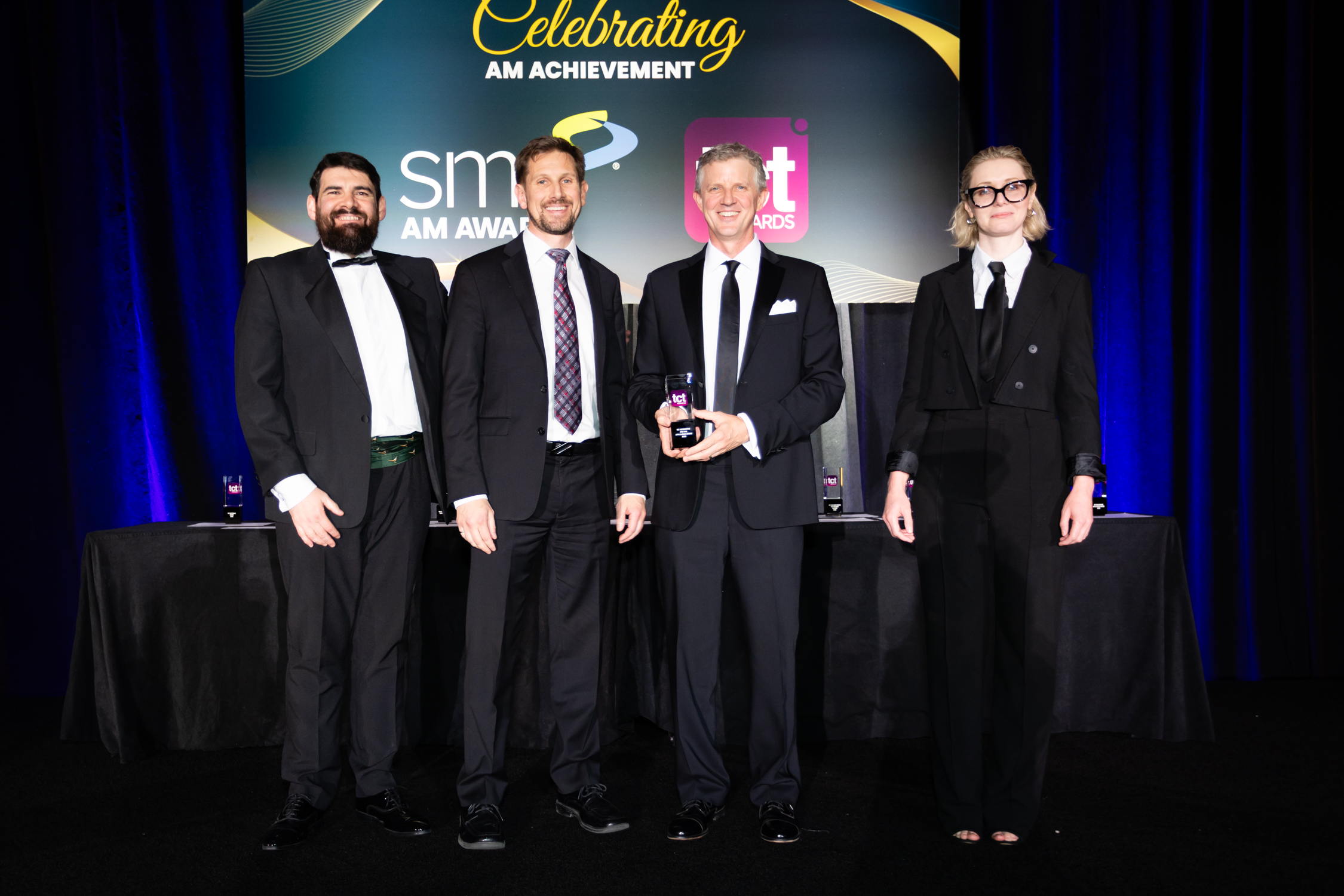 Group of award recipients on stage at TCT Awards 2026 holding Automotive and Rail Application Award trophy. 